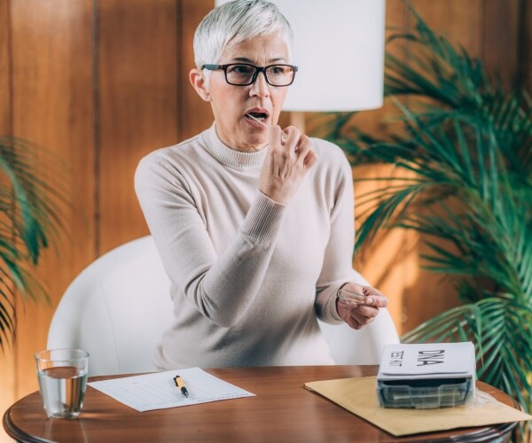 woman with an at-home genetic testing kit, taking a sample with mouth swab