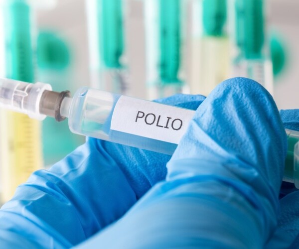 a close-up of hand with surgical glove holding a syringe labeled 'polio'