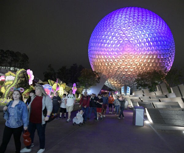 guests walk past the spaceship earth attraction at the walt disney world epcot theme park.