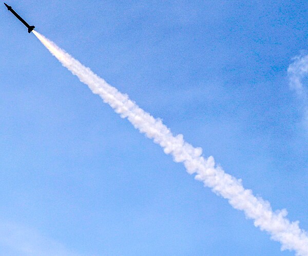 a missile flies with its exhaust flowing from the top left to the bottom right