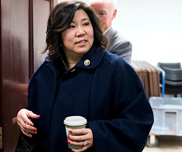 grace meng holds a cup of coffee as she walks through a doorway