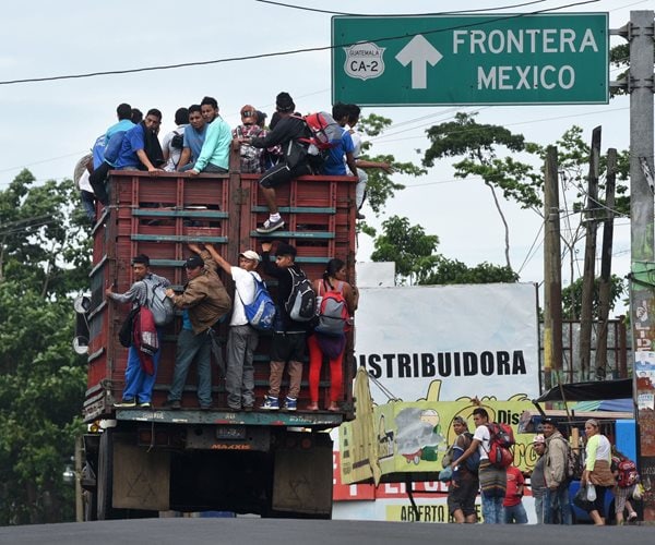 open truck piled high with migrants headed for mexico's southern border