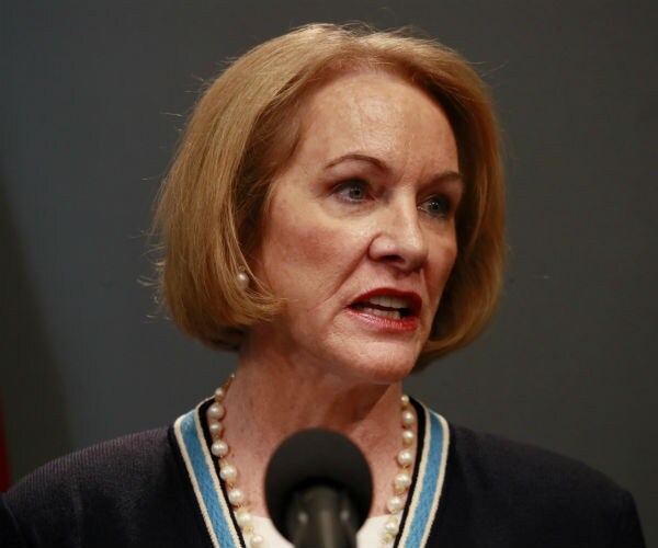 Seattle Mayor Jenny Durkan is shown speaking with the us flag in the background