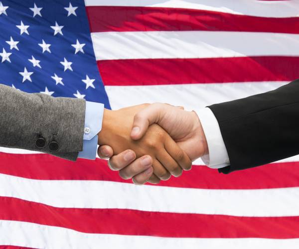 two men giving a handshake over an american flag background