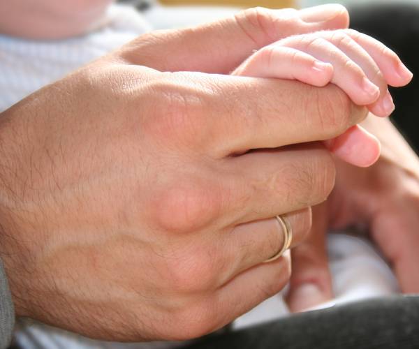 a mans hand holding the hand of a small child