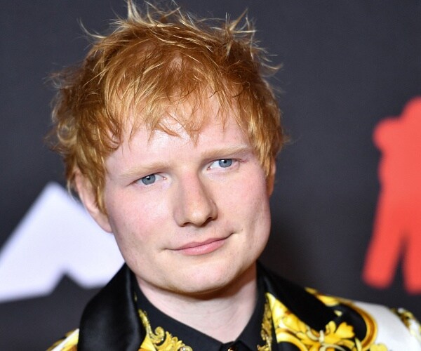 ed sheeran stands on red carpet