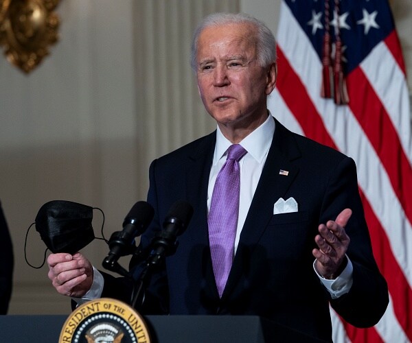 joe biden speaks while holding mask