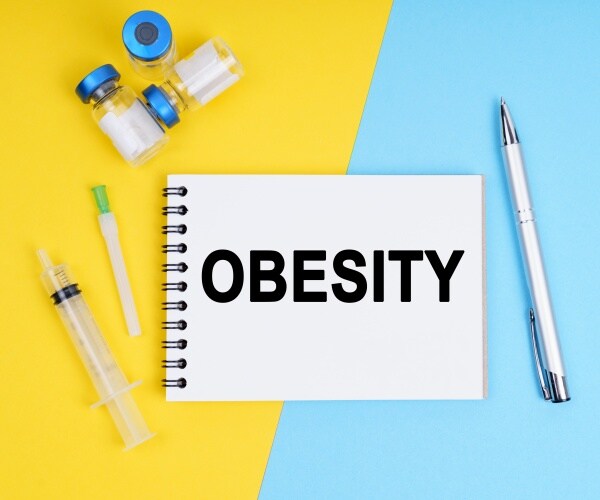 'Obesity' title on notebook, syringe, vials of weight loss drug