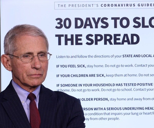 dr. fauci stands next to a stop the spread graphic