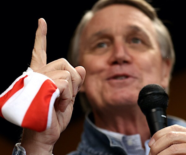 david perdue points upward defiantly during a campaign rally speech