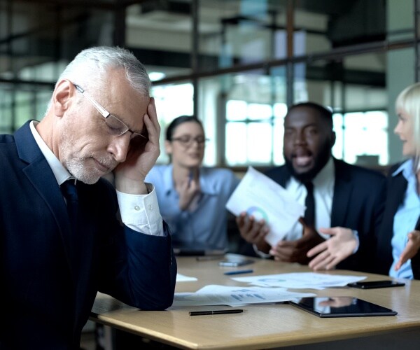 business meeting at work, employees arguing, one looking very stressed, worn out