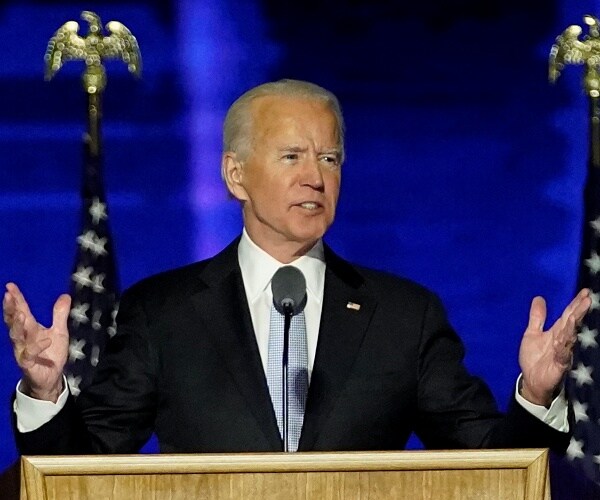 joe biden stand behind podium with hands raised