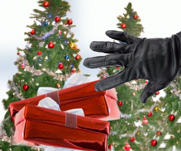 black-gloved hand of a thief stealing Christmas gifts next to christmas trees trees