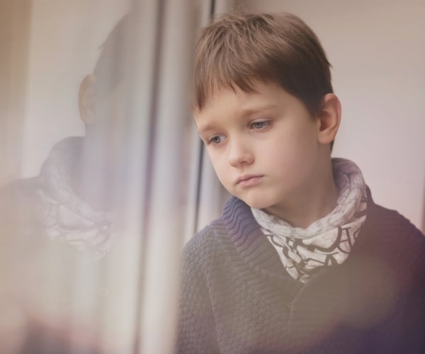 young boy with autism looking anxiously out window