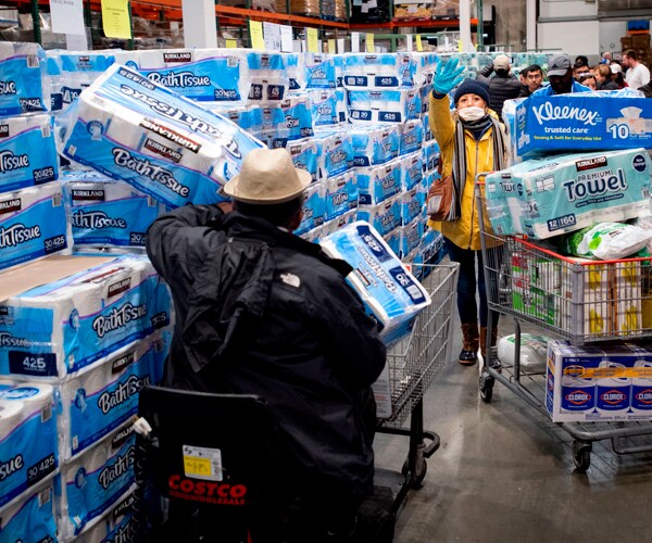 people load toilet paper into their shopping carts at a store