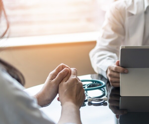 woman talking to doctor, wringing her hands b/c nervous, depressed