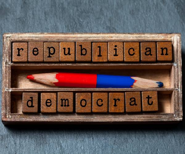 republicans and democrats written in wood block letters with a double sided red and blue pencil in the center