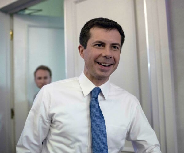 pete buttigieg is shown smiling in a white dress shirt and blue tie