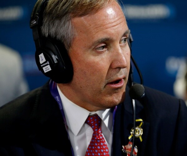 paxton in a suit and red tie with a headset on