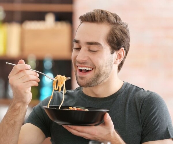 man eating a bowl of spaghetti