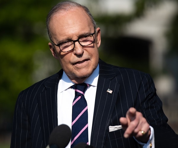 larry kudlow stands outside the white house and speaks at a microphone