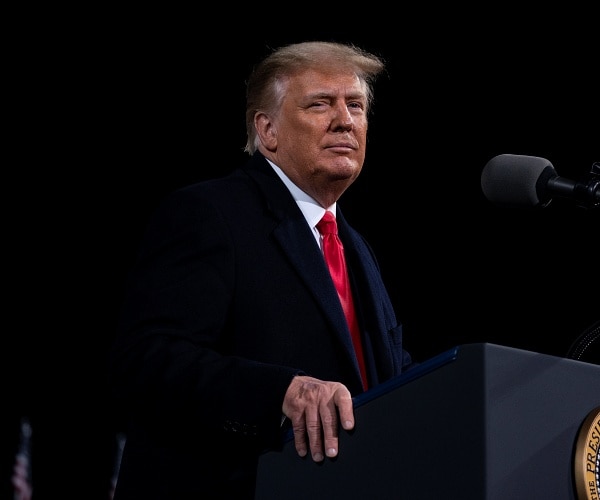 donald trump stands behind podium at rally