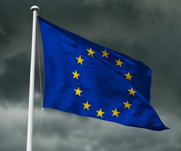 european union flag with storm clouds in the background