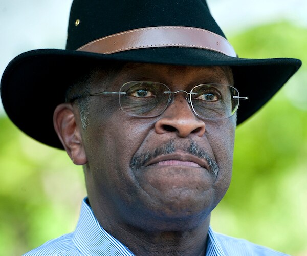 herman cain smiles wearing a black cowboy hat