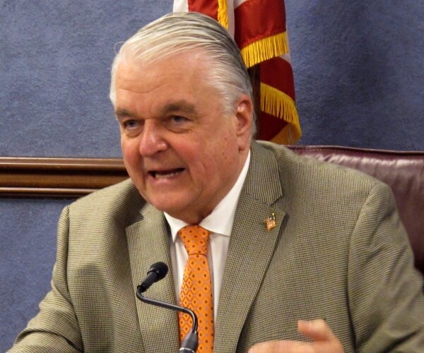 steve sisolak in an orange tie and light tan suit