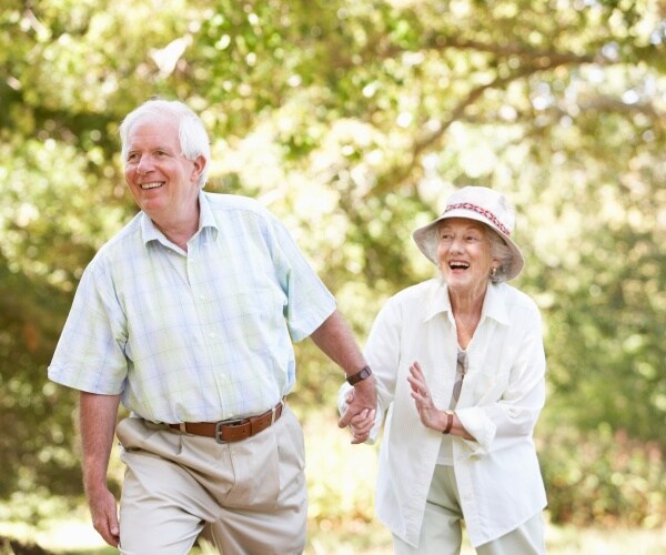 older man and woman walking in park