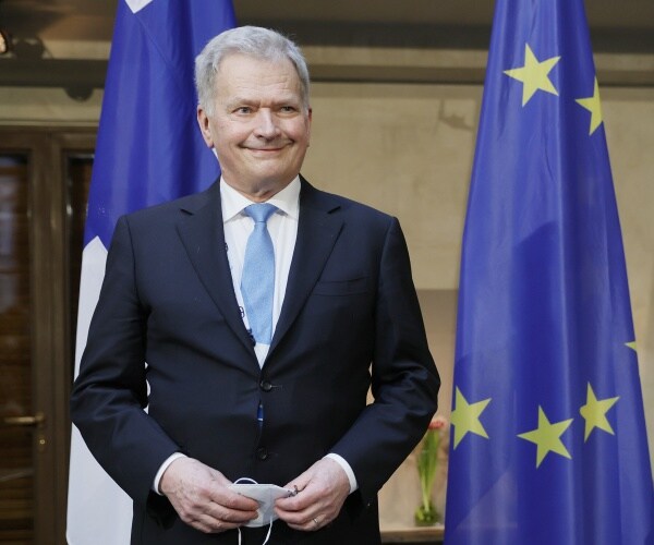 president sauli niinisto poses for a photo in front of flags