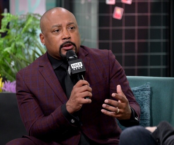 daymond john wearing a burgundy suit and black shirt speaking into a microphone