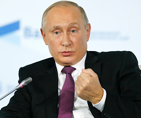 vladimir putin makes a fist with his left hand while speaking during a news conference