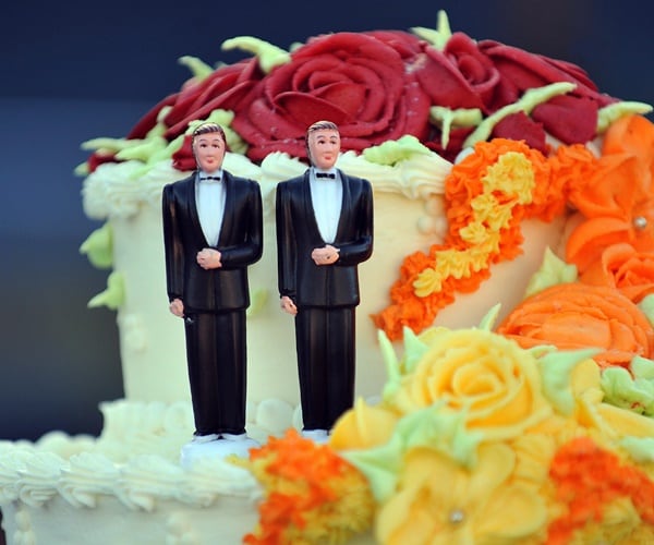 two grooms on top of a wedding cake