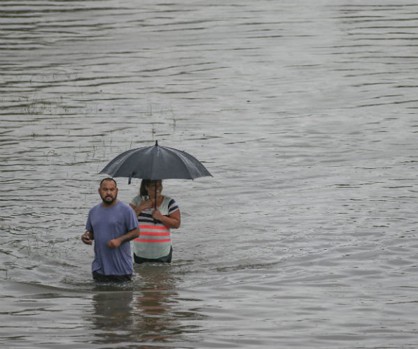 a man and woman wade through floodwater