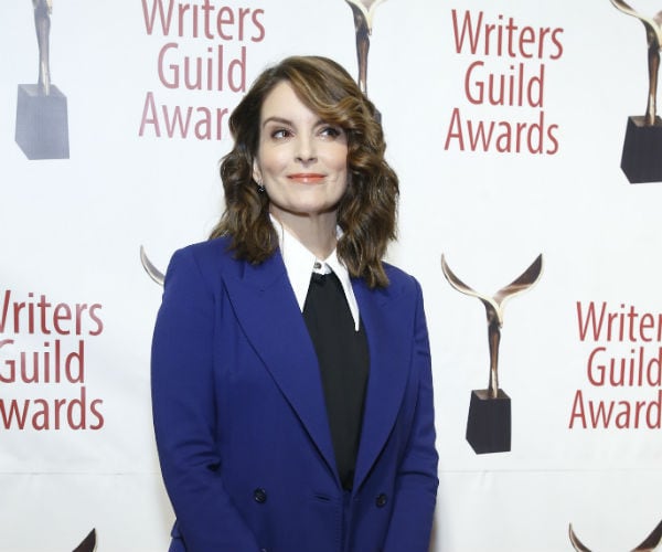 tina fey is shown in a cobalt jacket, white dress shirt and black neck tie