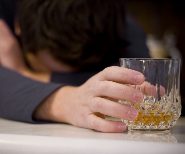 man with head on table, drink in hand