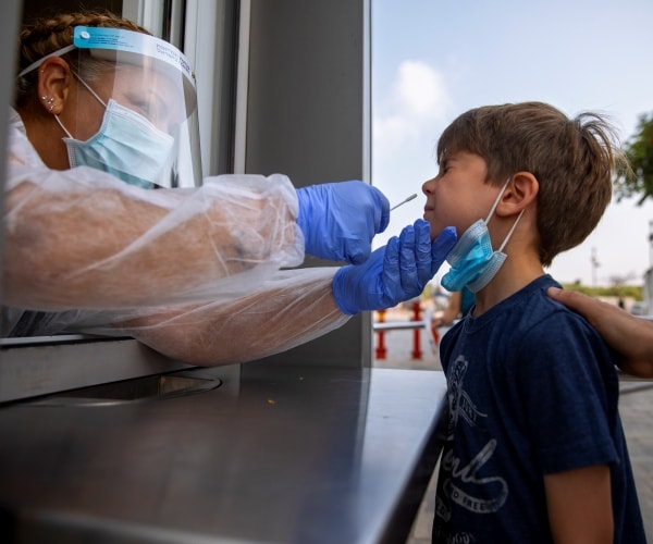 A health worker collects a swab sample from a kid to test for COVID-19.