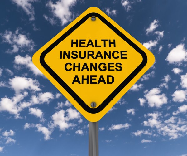 a road sign reading health insurance changes ahead against a blue sky with puffy white clouds