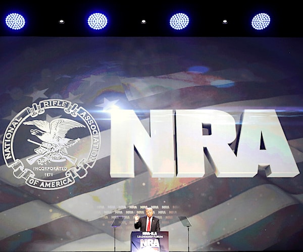 national rifle association logo and signage appears above president donald trump speaking