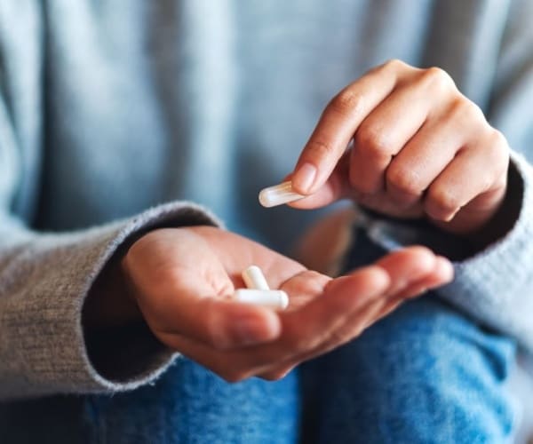 person with pills in hand, taking one