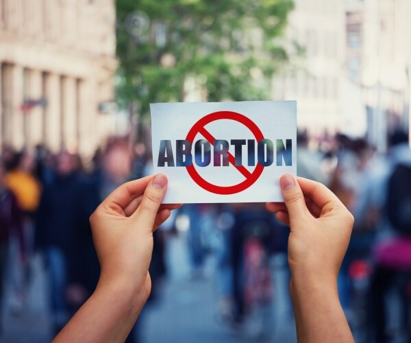 activist hands holding a banner with stop abortion message over a crowded street background