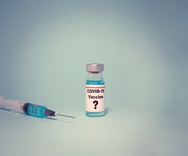 photo of a syringe and a vial of COVID vaccine with a question mark