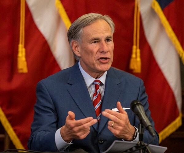 abbott in a blue suit and striped red tie 