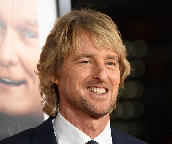 owen wilson stands on red carpet