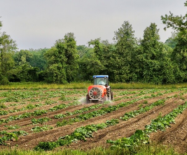 Tractor spraying pesticide on crops 