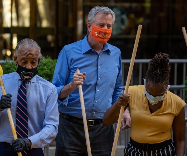 de blasio helps paint a blm mural on the road outside