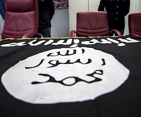 the black and white flag of the islamic state in syria lays on a table