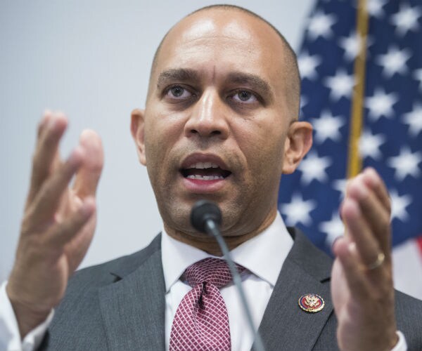 hakeem jeffries talking to members of the media in gray suit, white dress shirt and red tie