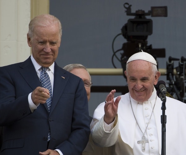 francis waves next to biden in a suit